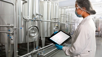 Woman standing in Food & Beverage production facility and checking the Netilion Asset Health status